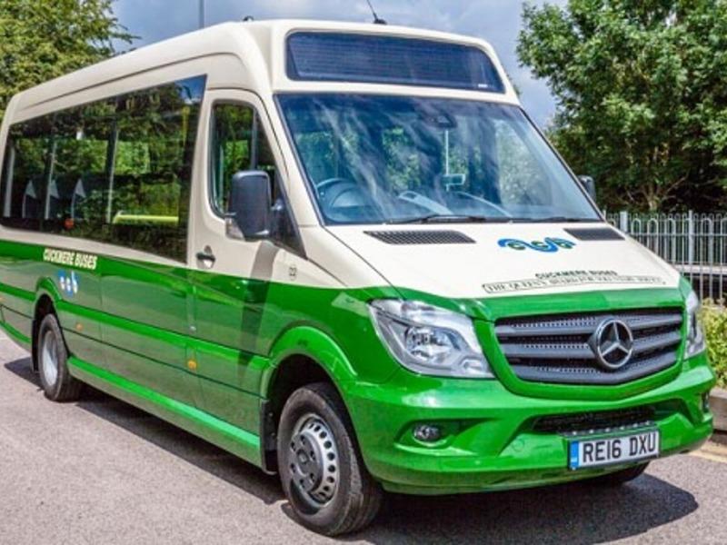 A green and white bus parked on the road